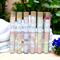 Whole Self Aromatherapy's bath salts in test tubes on a table with white linens, framed by greenery in back and a blue flower to the right.
